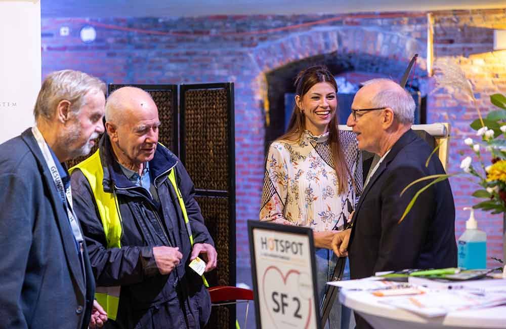 Eine Gruppe von Leuten steht um einen Tisch herum und unterhält sich miteinander.