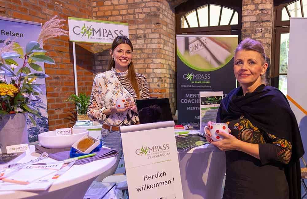 Zwei Frauen stehen nebeneinander an einem Tisch und halten Tassen.