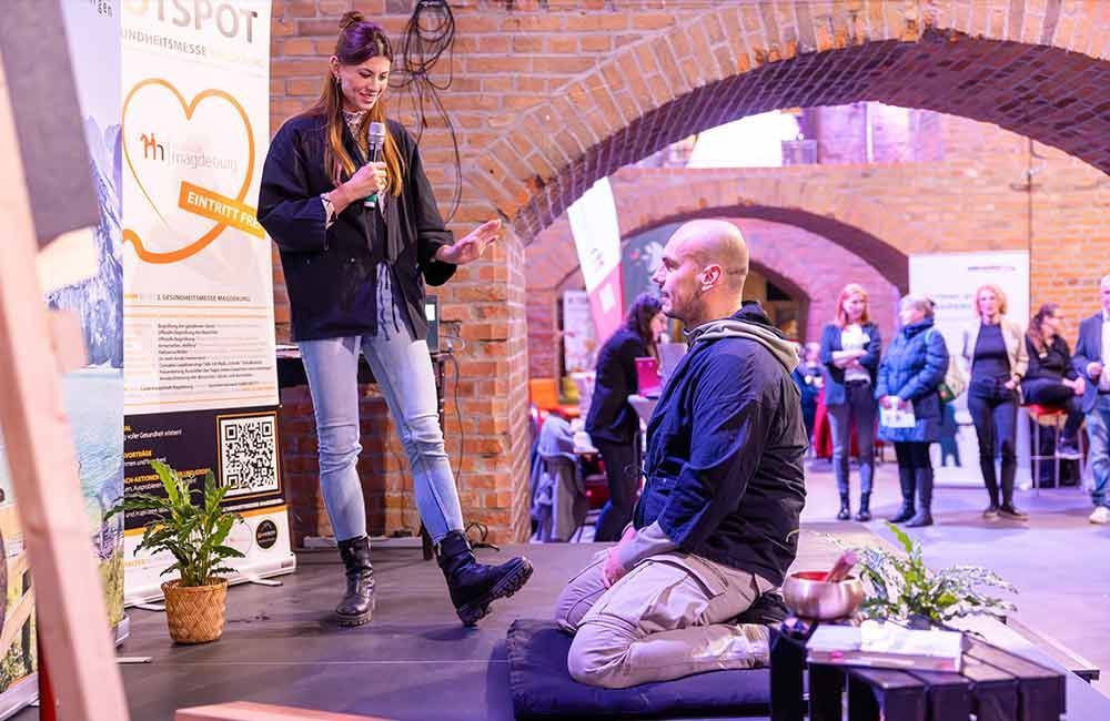 Ein Mann kniet vor einer Frau, die ein Mikrofon hält.