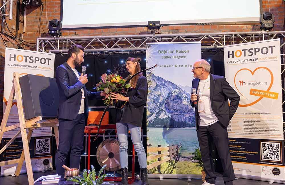 Eine Frau hält einen Blumenstrauß und steht neben zwei Männern.