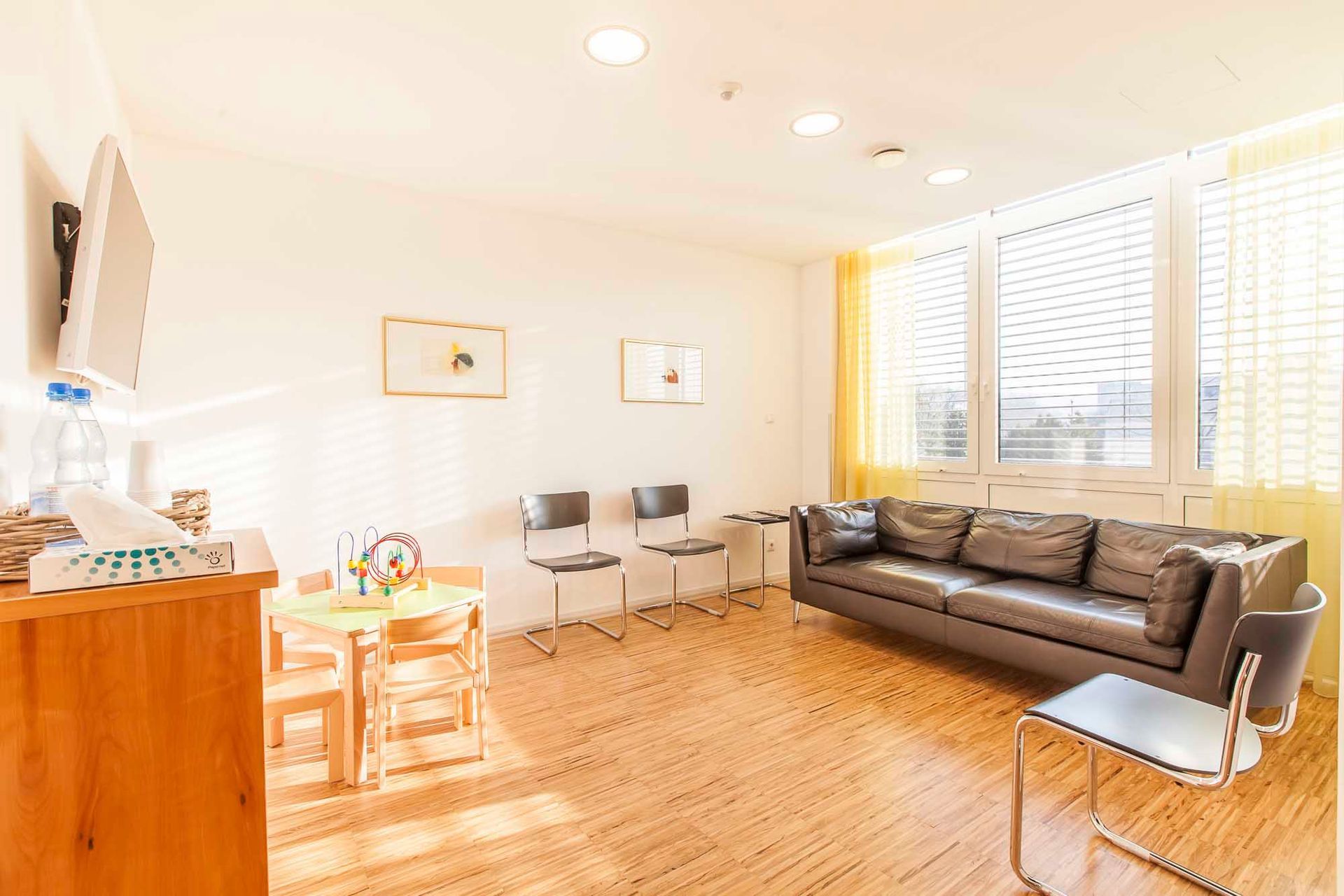 Ein Wartezimmer mit Couch, Stühlen und Tisch.