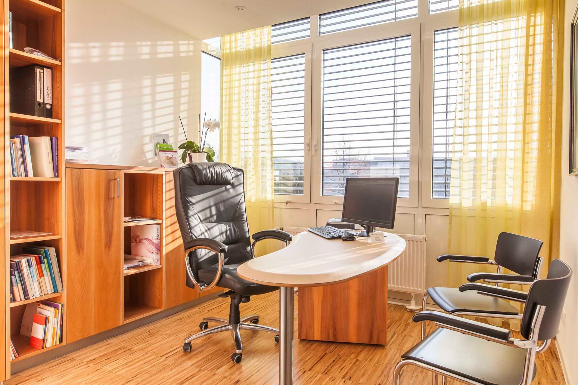 Ein Wartezimmer mit Schreibtisch, Stühlen und einem großen Fenster.