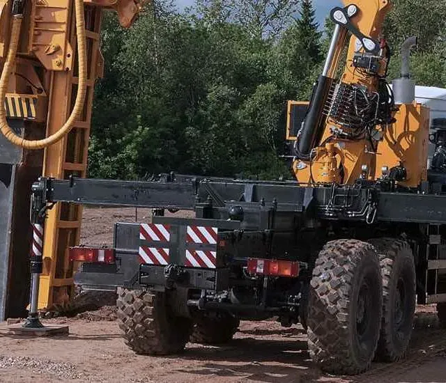 Un camión con una grúa acoplada está estacionado en un camino de tierra.