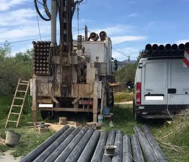 Una furgoneta blanca está aparcada al lado de una gran máquina.