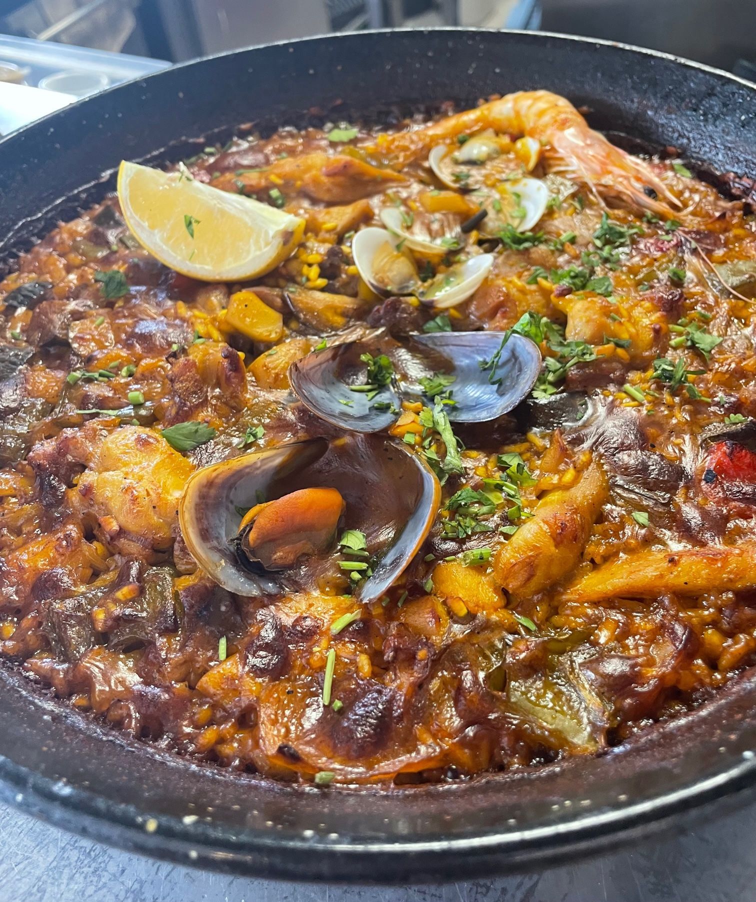 Un primer plano de una paella con mariscos y una rodaja de limón.