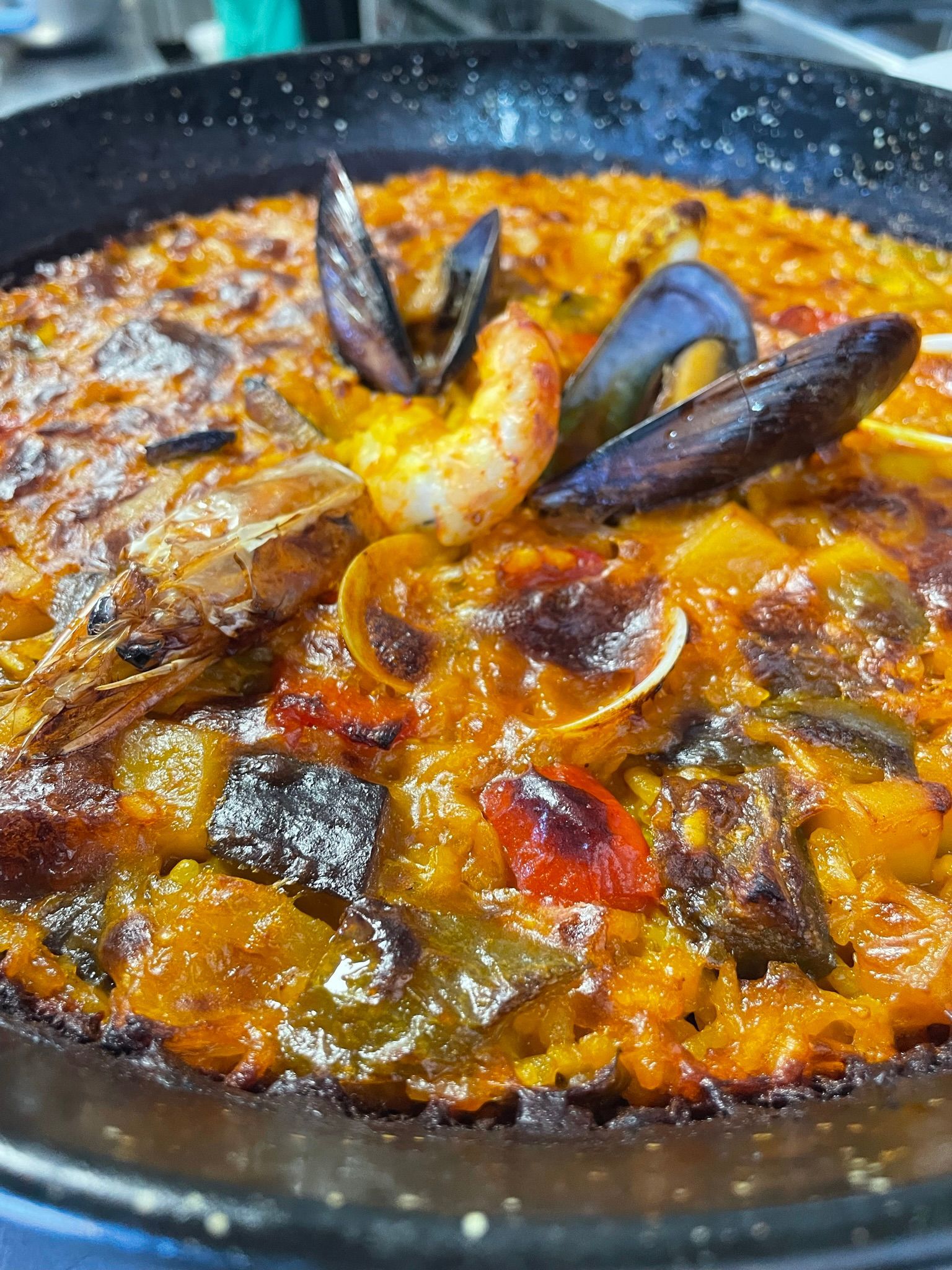 Un primer plano de una paella con camarones y mejillones.