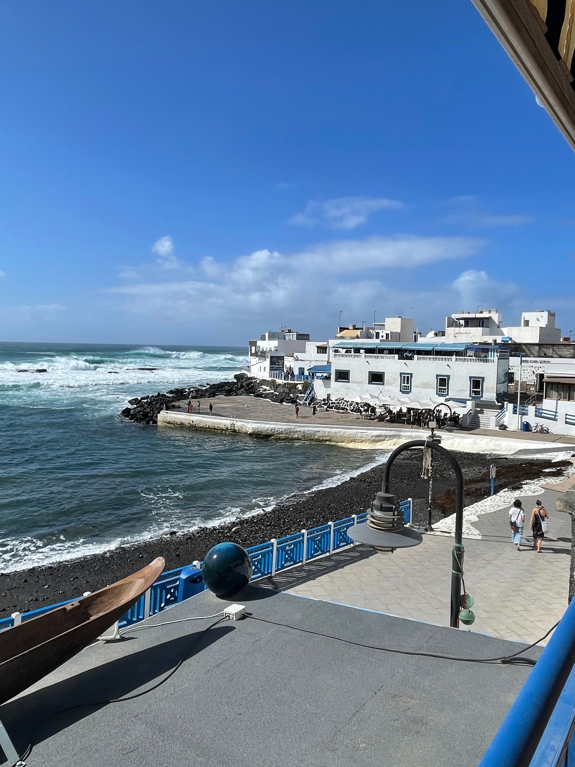 Una vista del océano desde un balcón con barandilla azul.