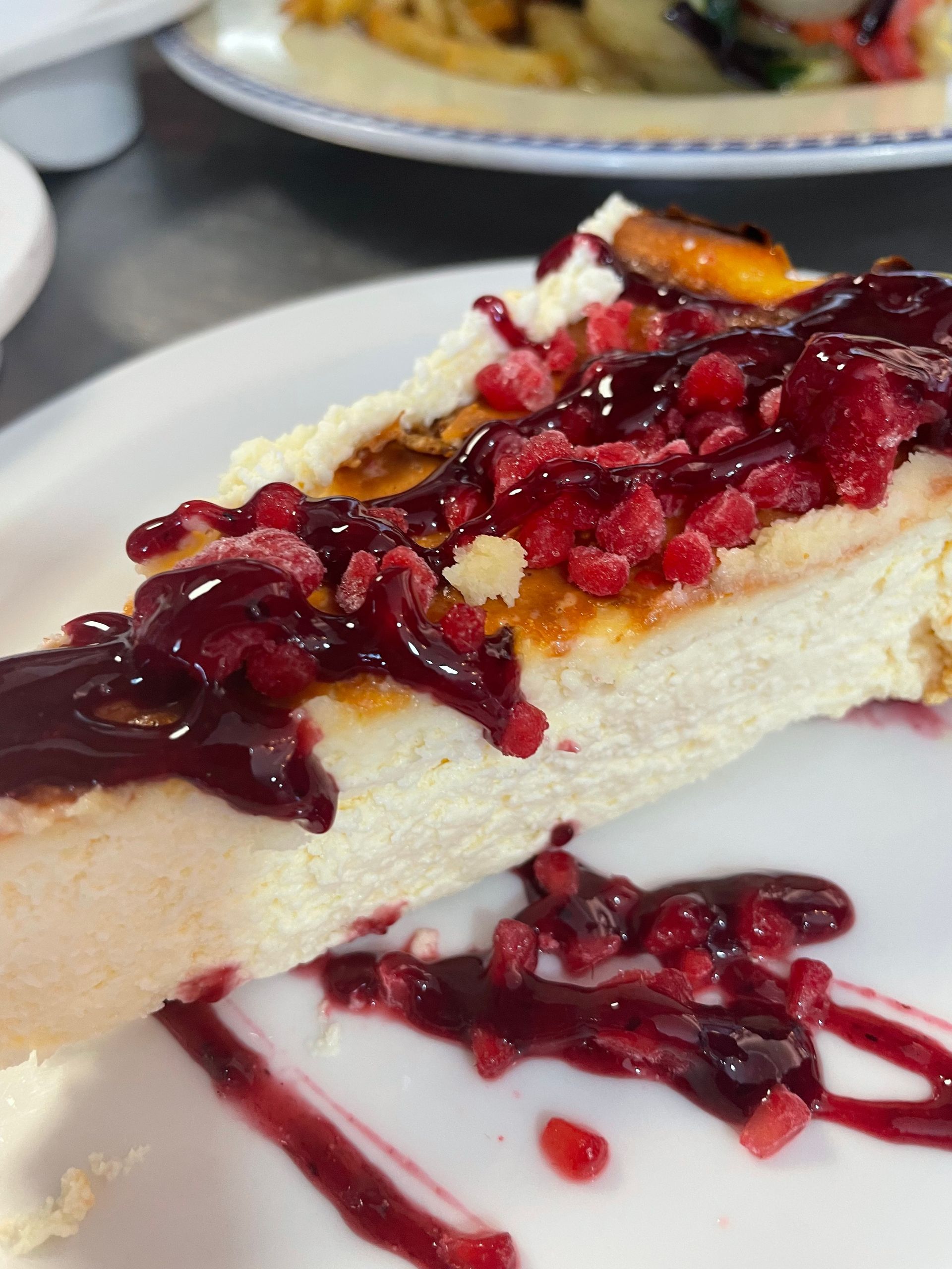 Una rebanada de tarta de queso con salsa de frambuesa en un plato blanco