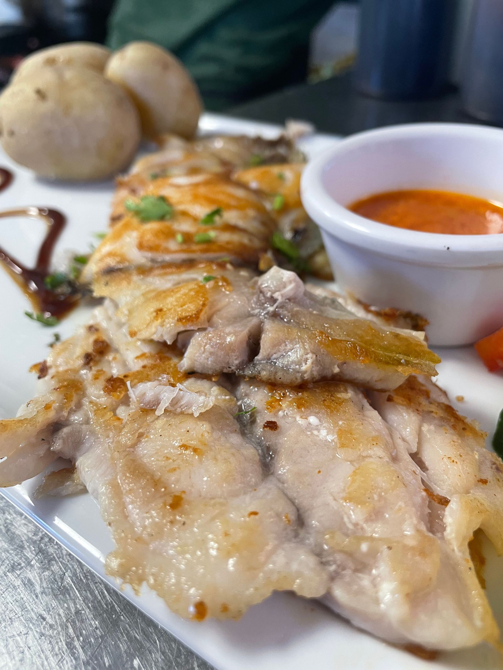 Un primer plano de un plato de comida con salsa y patatas sobre una mesa.