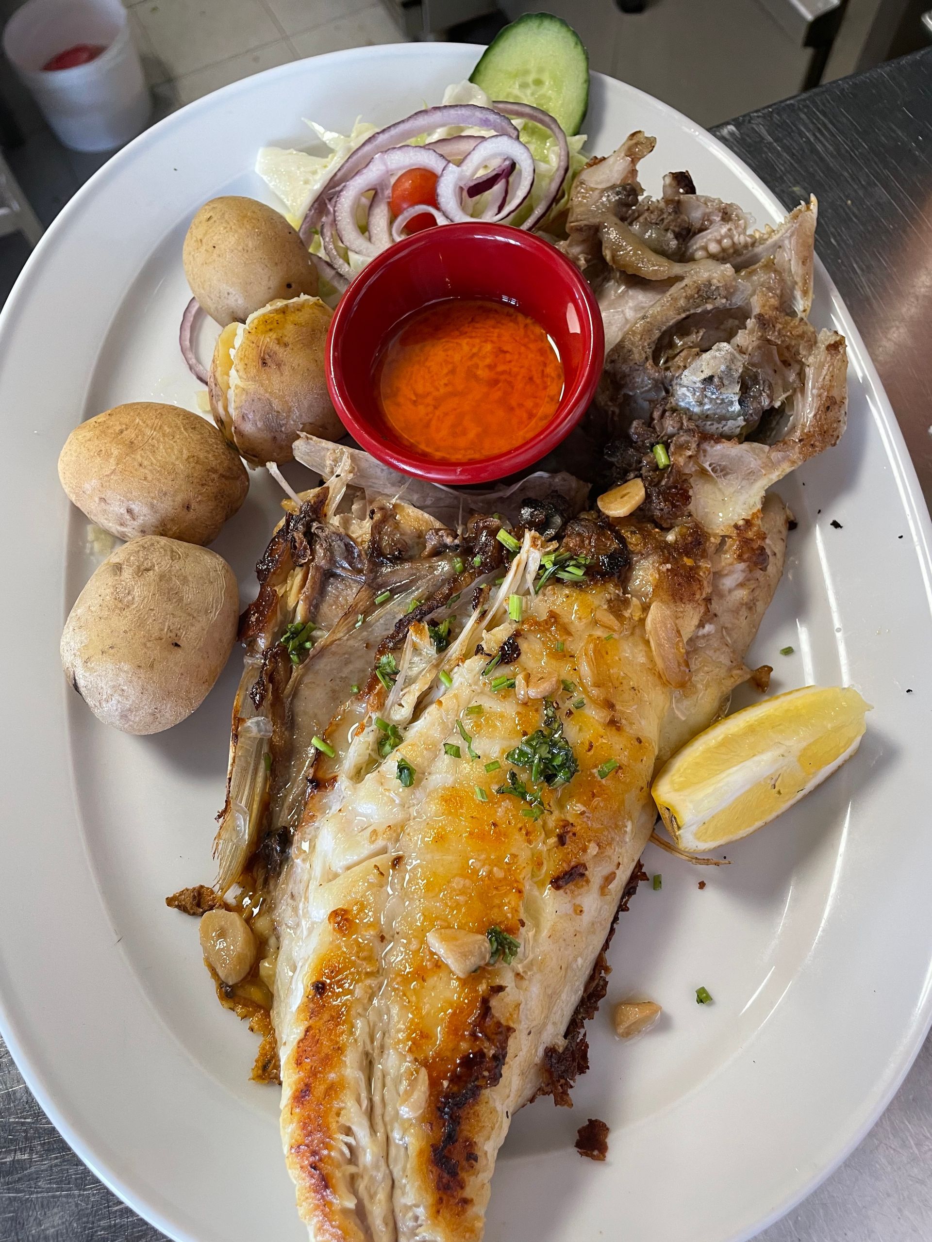 Un plato blanco cubierto con un gran trozo de pescado y patatas.