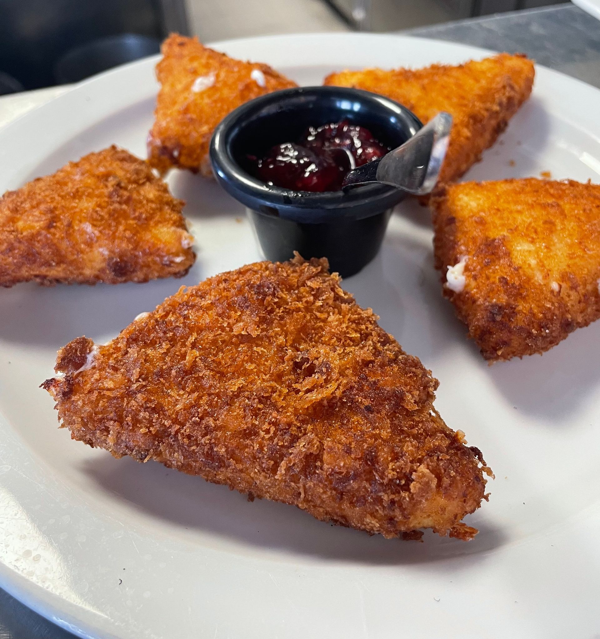 Un plato blanco cubierto con comida frita y un tazón pequeño de salsa.