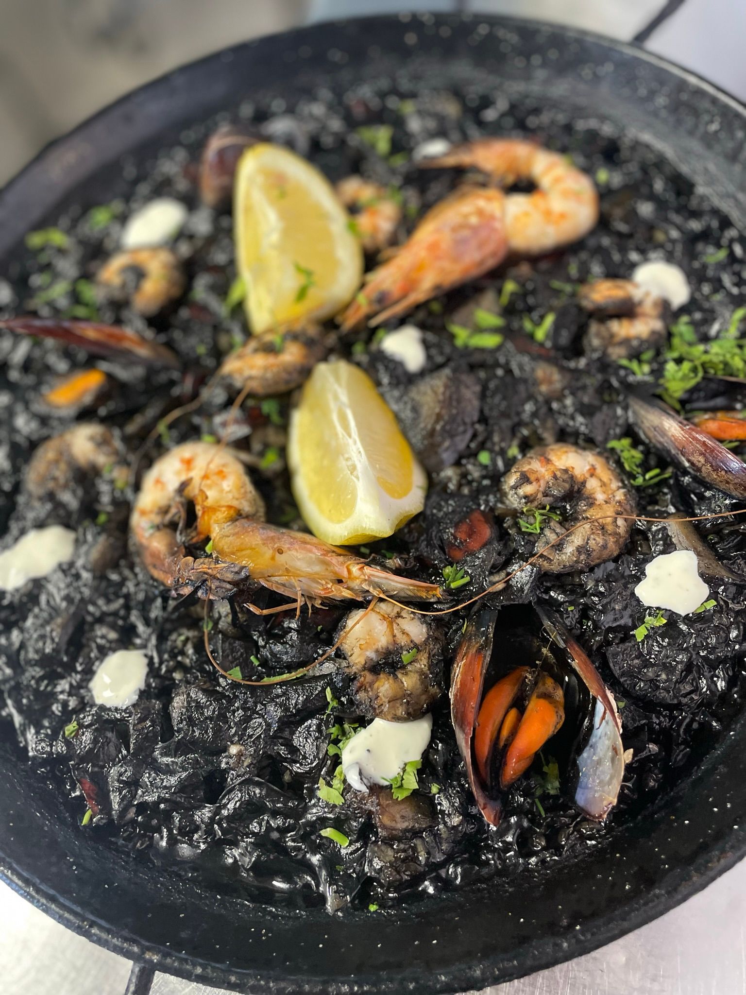 Un primer plano de un plato de comida con camarones y mejillones en una mesa.