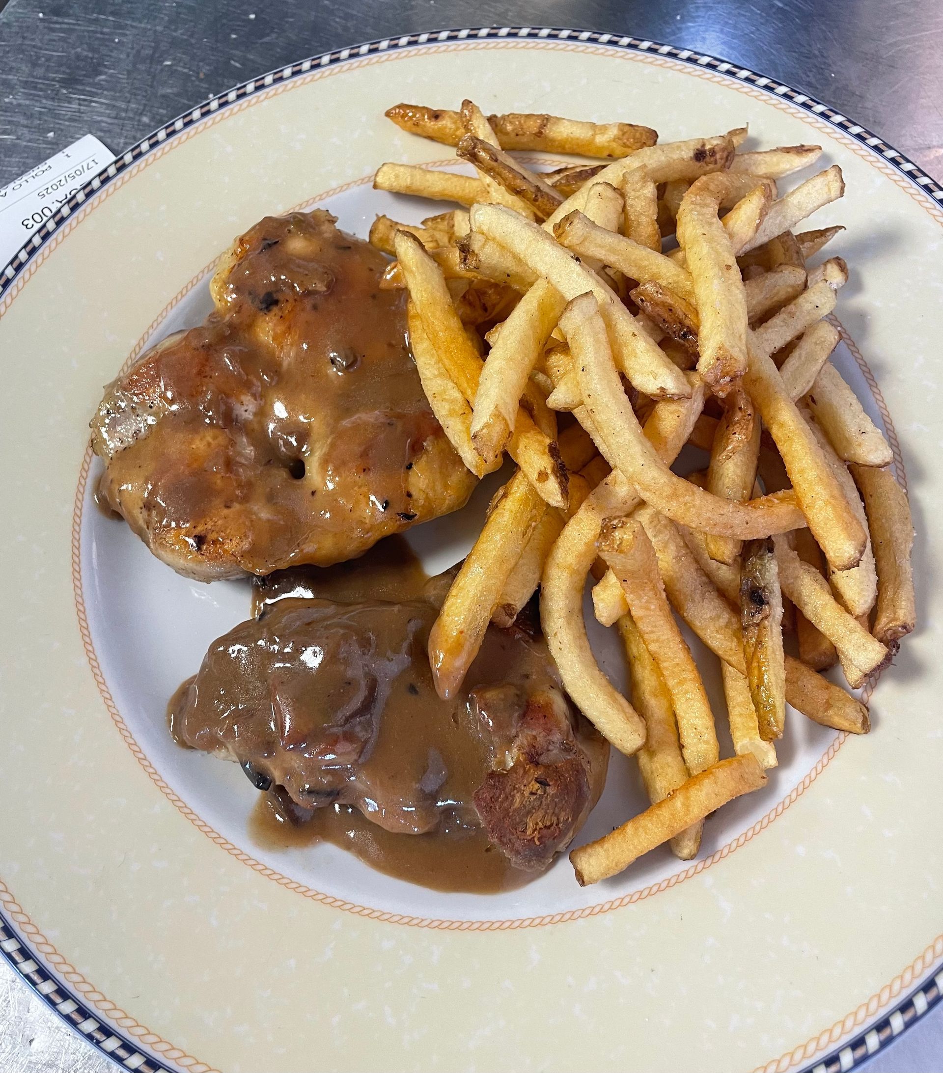 Un plato de comida con carne y patatas fritas en una mesa.