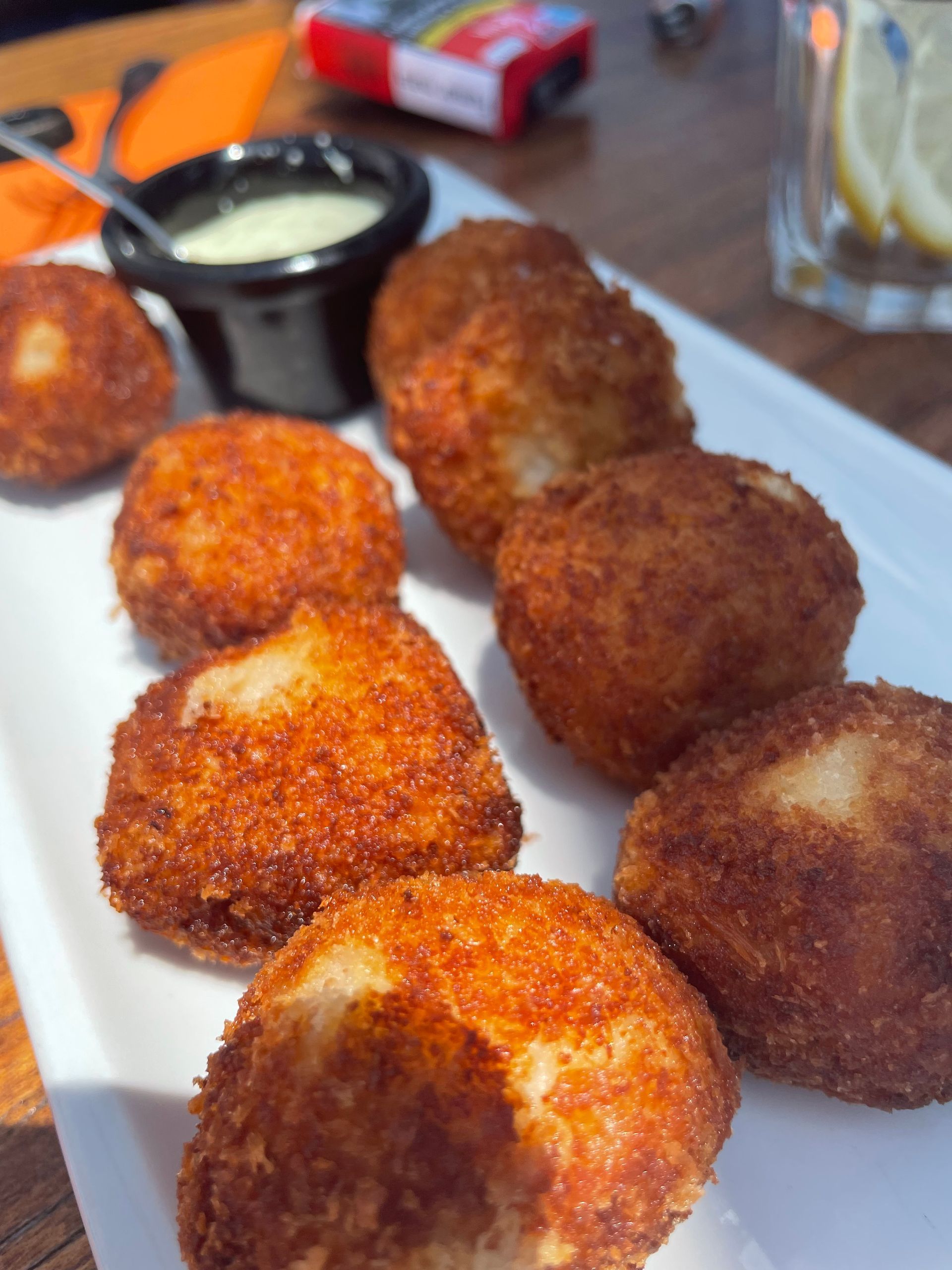 Un plato blanco cubierto con comida frita y una salsa para mojar.