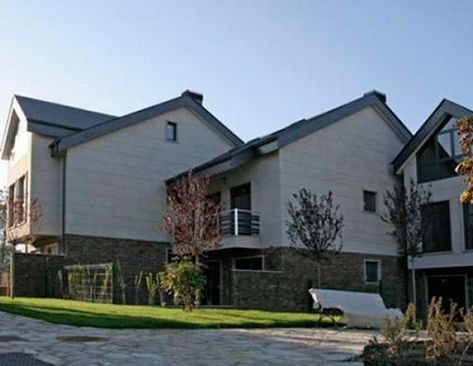 Una casa grande con un banco blanco delante de ella.