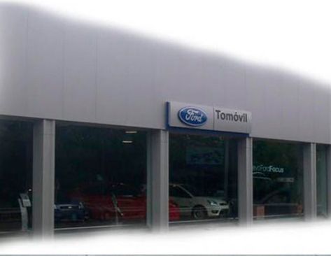 Un concesionario Ford con coches aparcados delante.