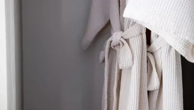 Una túnica blanca cuelga en una puerta al lado de una almohada.