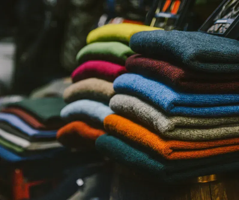 Una pila de suéteres de diferentes colores se apilan uno encima del otro.