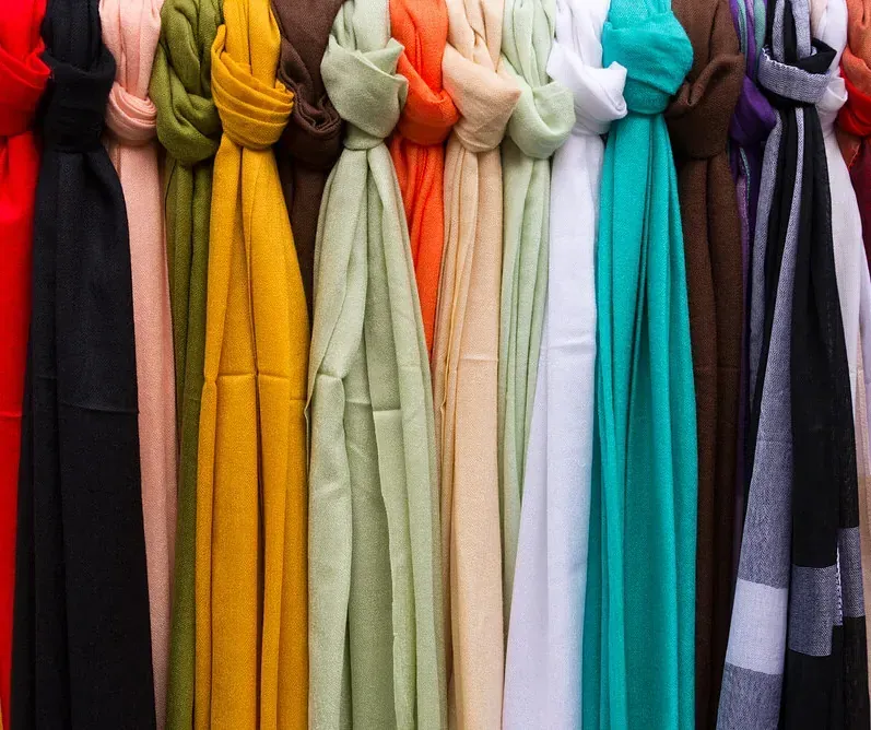 Una hilera de bufandas de diferentes colores cuelgan de un perchero.