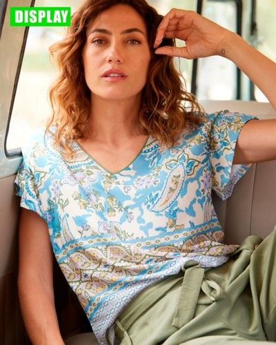 Una camisa azul con lunares blancos tiene una etiqueta adherida.