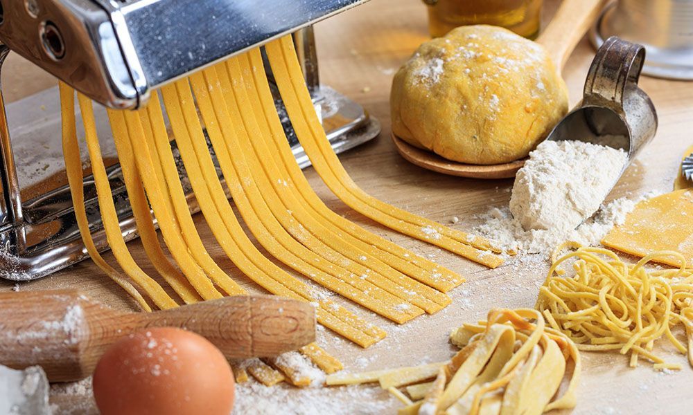 Auf einem Holztisch stellt eine Nudelmaschine Nudeln her.