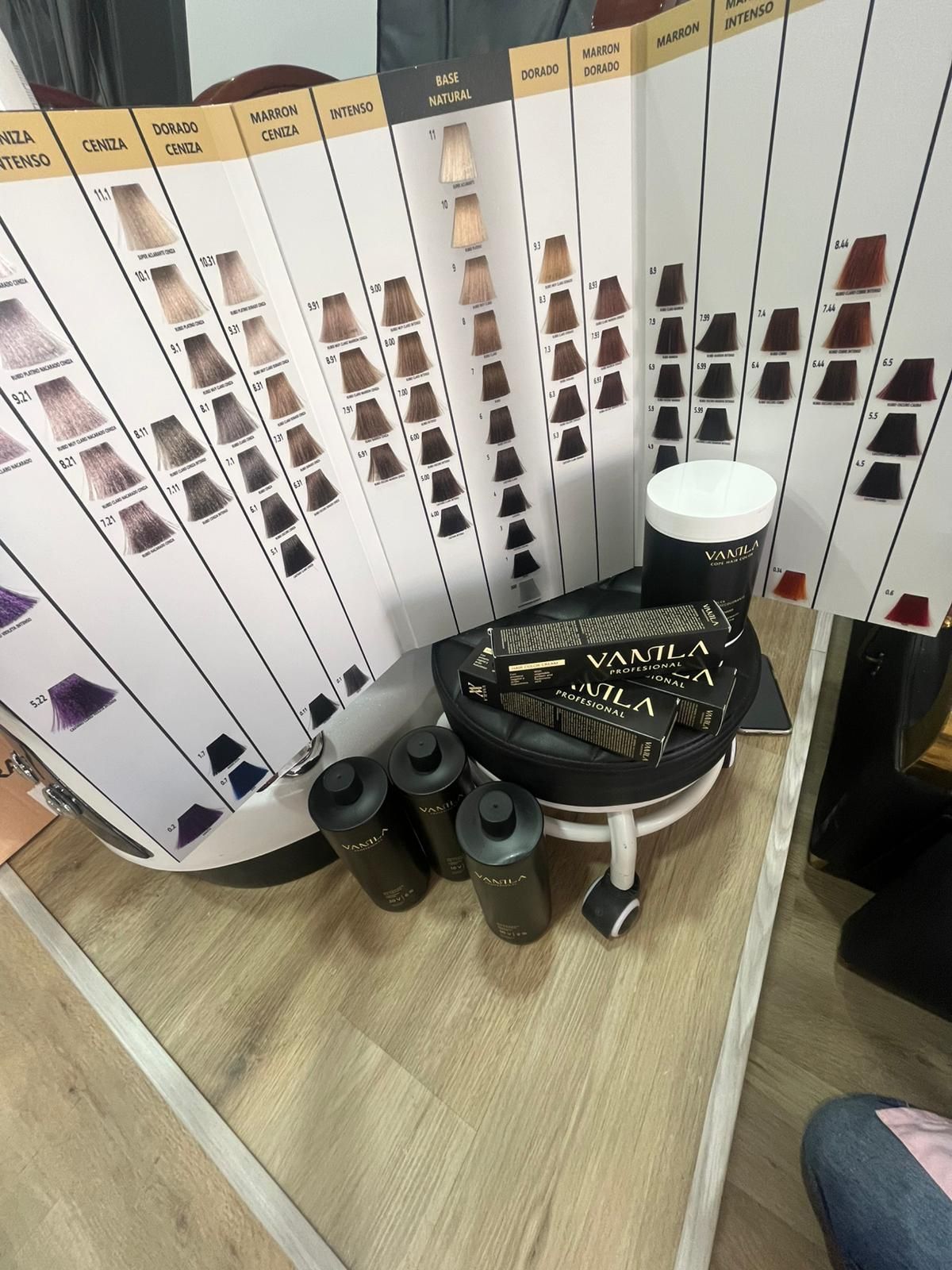 Exhibición de muestras de color de cabello sobre una mesa con tazones, vasos y pequeños recipientes en un ambiente similar al de una peluquería.