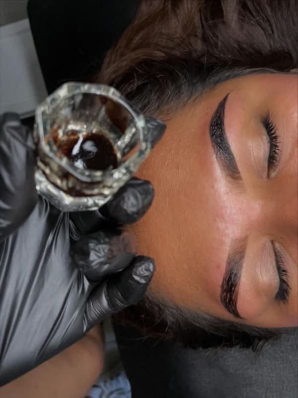 Primer plano de un ojo con pestañas largas y oscuras. El iris es marrón verdoso con un reflejo blanco brillante.