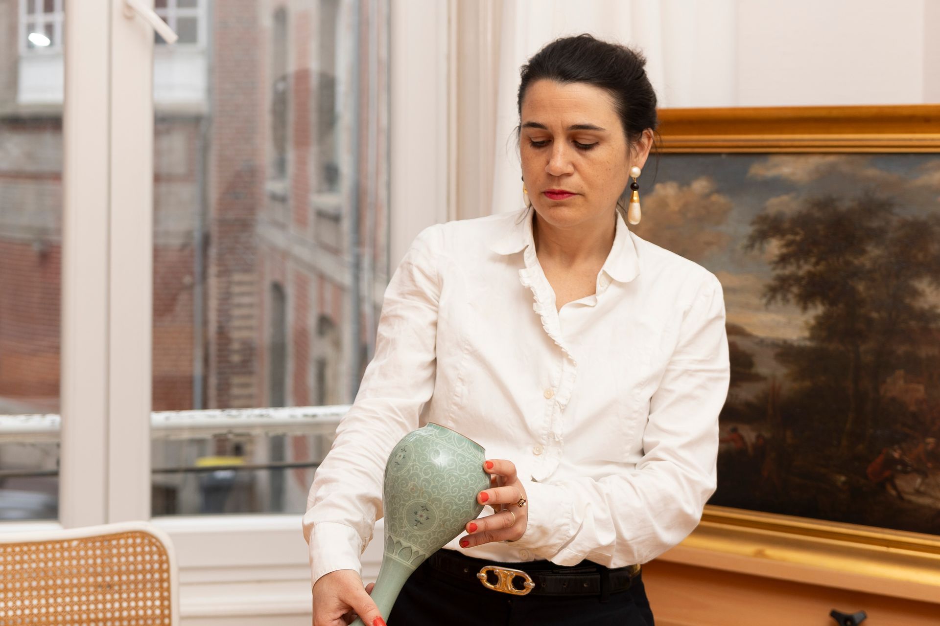 Une dame regardant l'arrière d'un vase en céramique.
