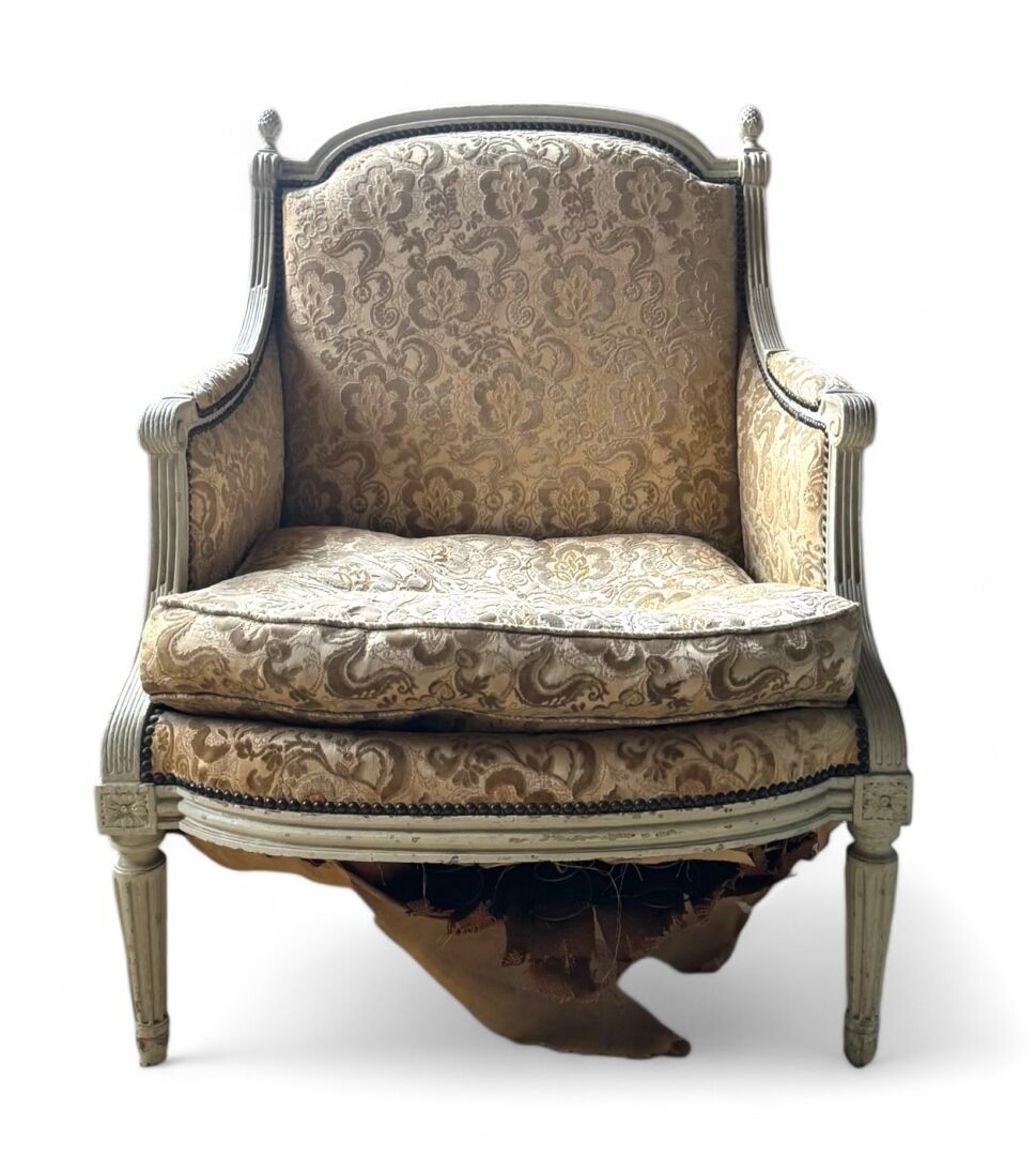 Fauteuil ancien endommagé avec tissu fleuri et cadre blanc vieilli.