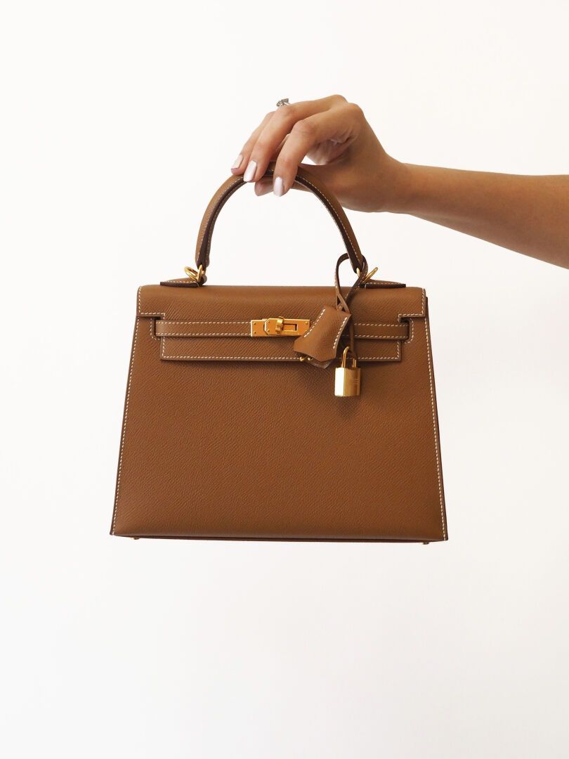 Une personne portant un sac à main Hermès marron.