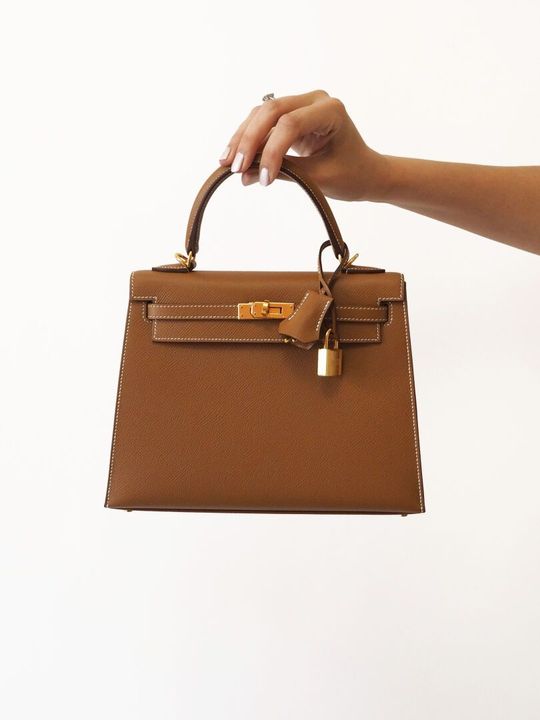 Une personne portant un sac à main Hermès marron.