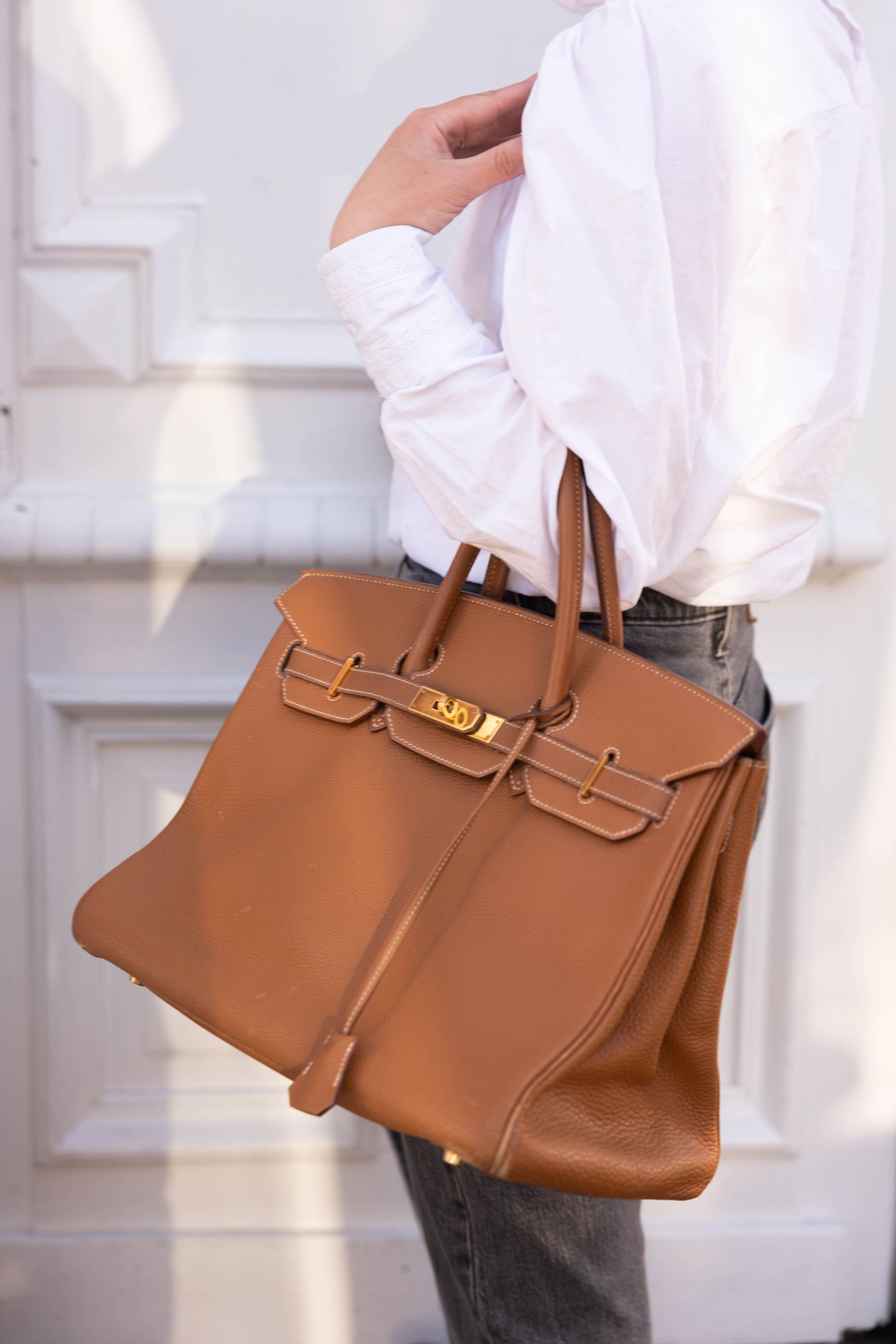 Un sac à main de couleur brun au bras d'une femme.