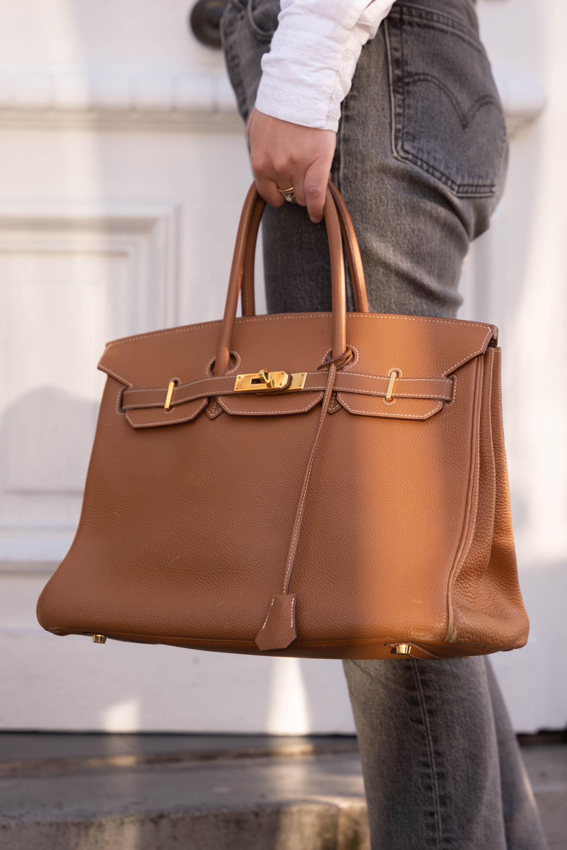 Une personne tenant dans ses mains un sac de luxe marron.