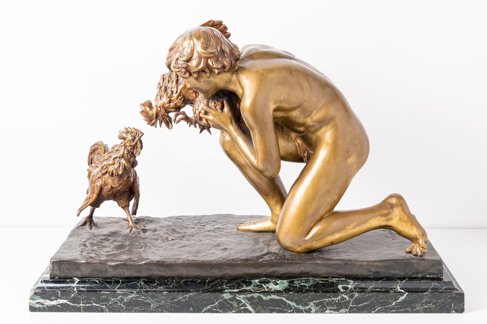Sculpture en bronze d'une personne nue agenouillée près d'un coq, tous deux sur un socle en marbre.