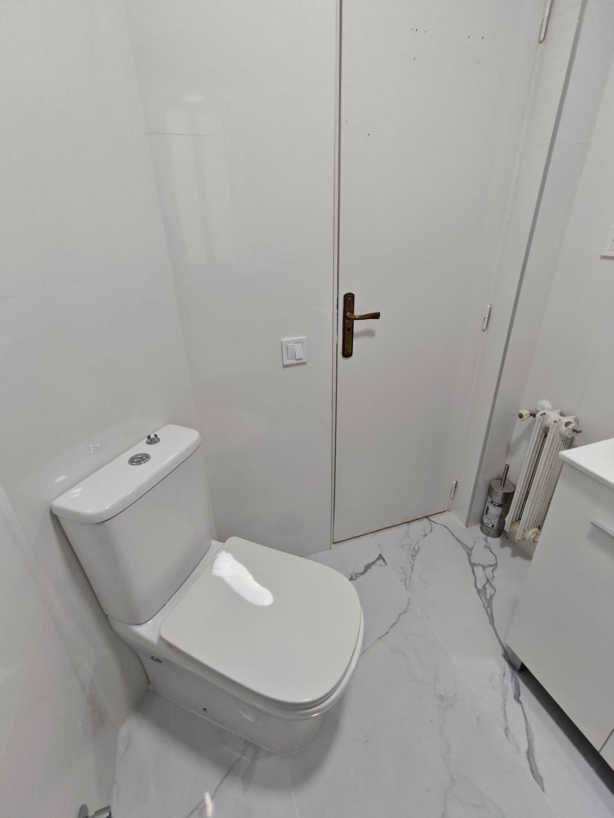 Inodoro blanco en un baño pequeño, completamente blanco.