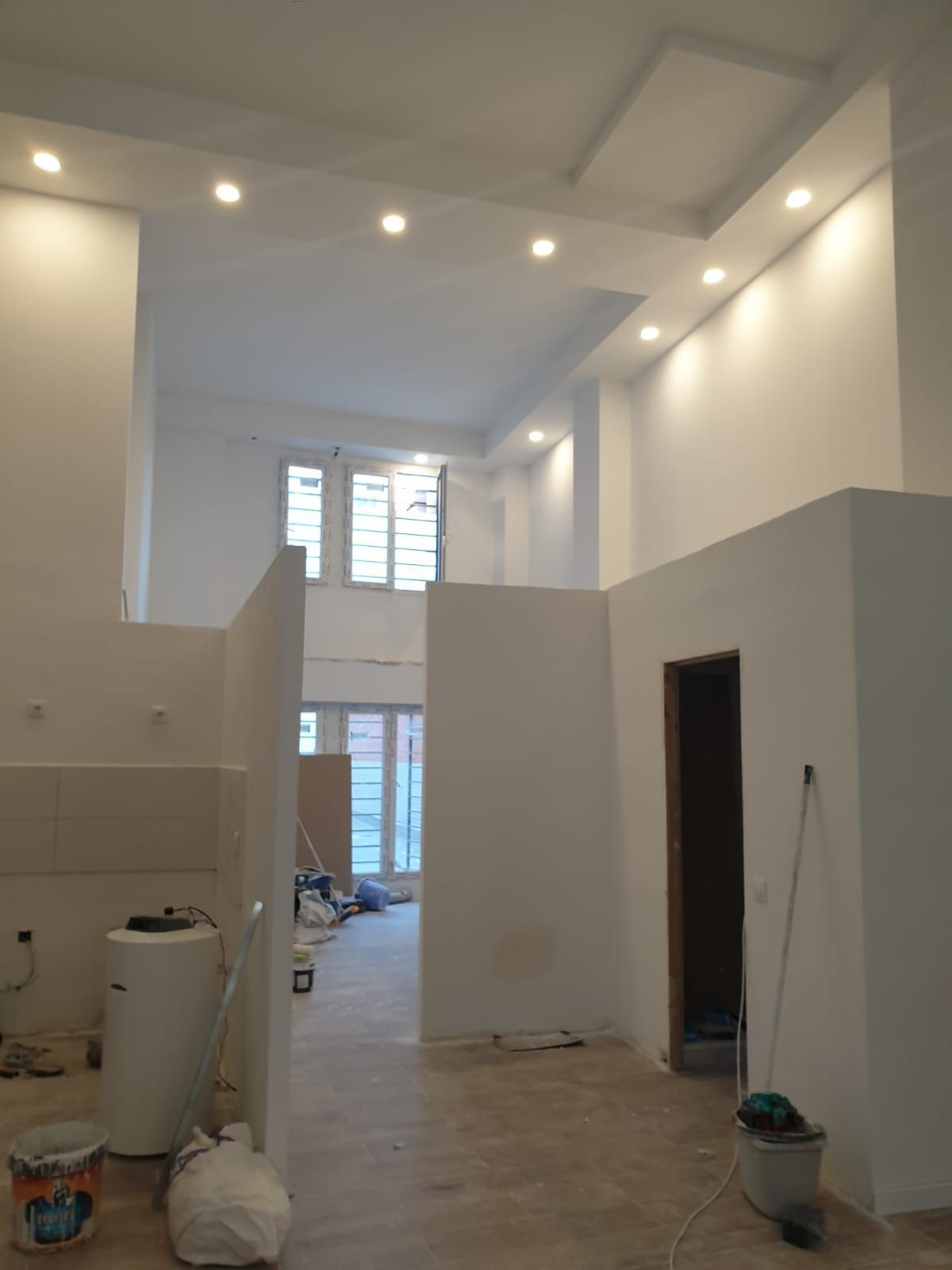 Espacio parcialmente renovado, con paredes blancas y luces empotradas. 