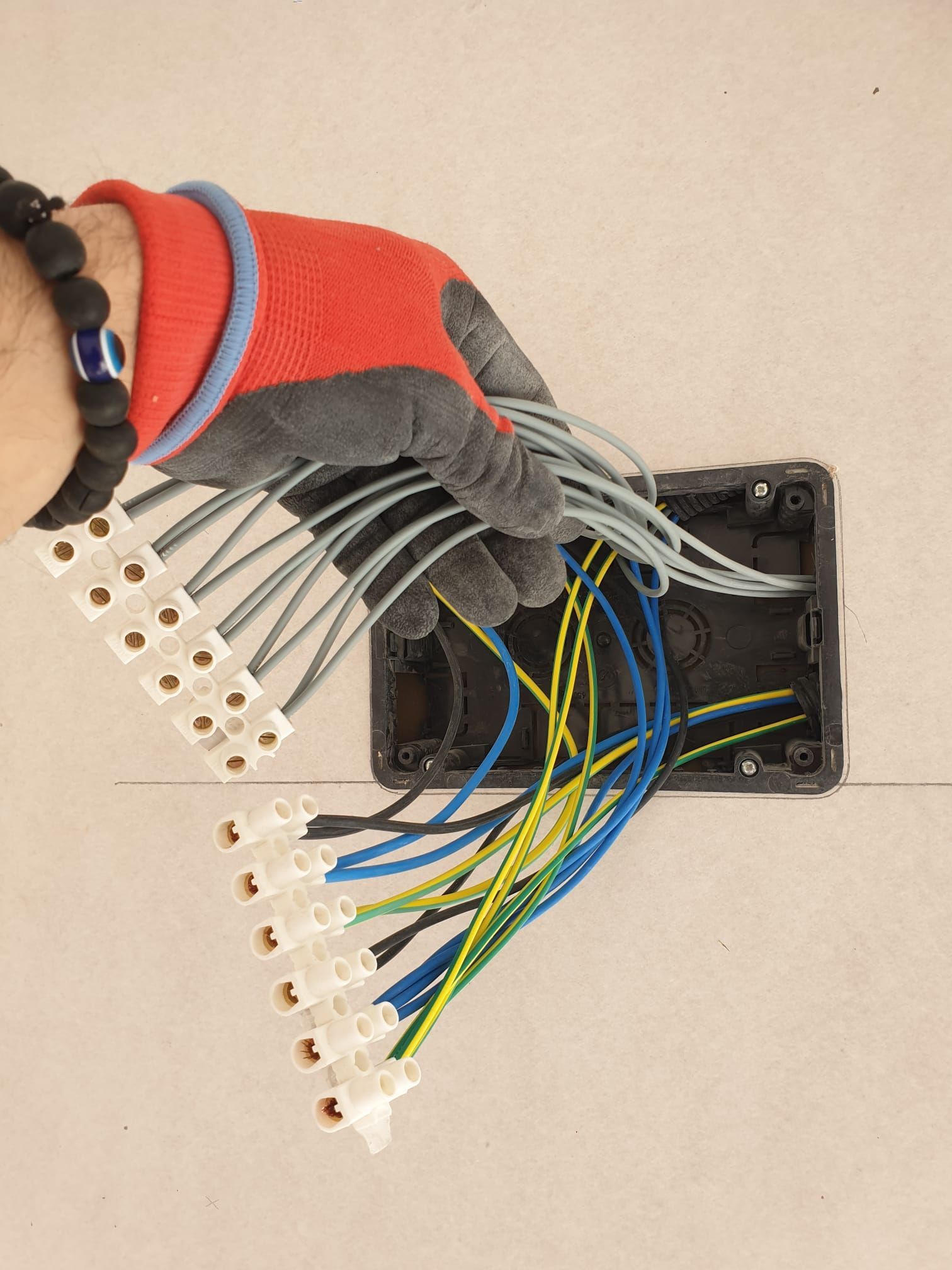 Una mano enguantada que sostiene un manojo de cables eléctricos conectados .