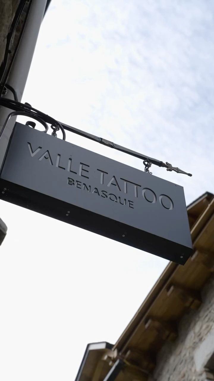Un cartel de Valle Tattoo cuelga del costado de un edificio.