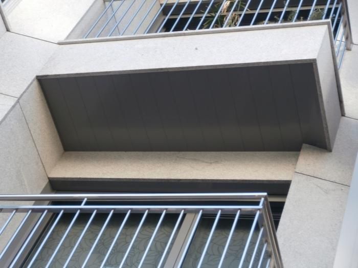 Exterior del edificio con balcón y barandillas metálicas. Techo pintado de gris con rejas en la parte superior.