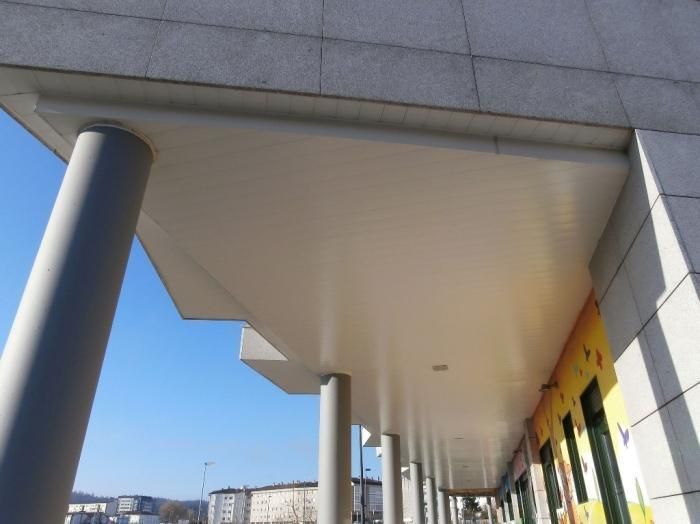 Columnas grises sostienen un voladizo blanco, parte de la fachada de un edificio.