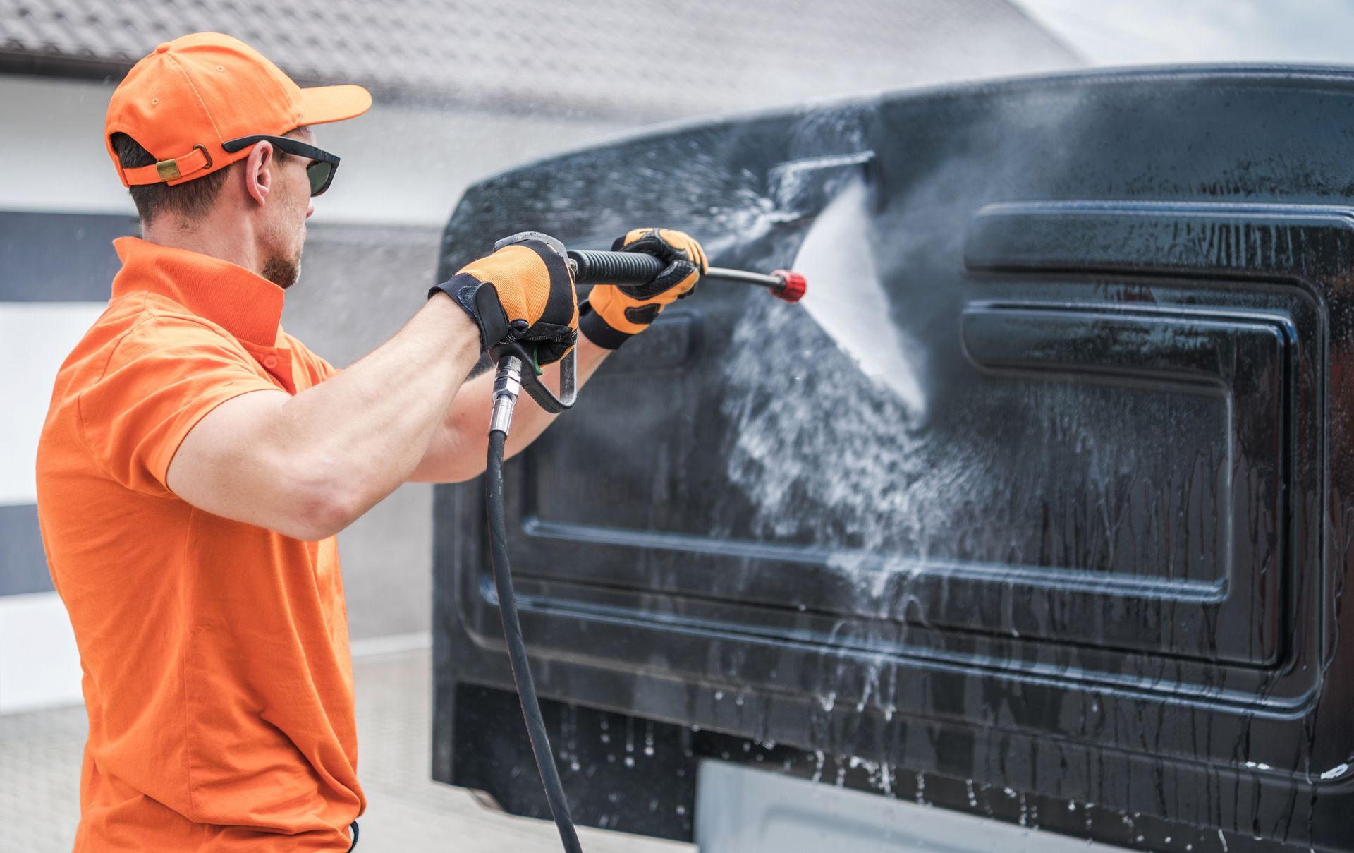 Camioneta roja siendo lavada a presión en un lavadero de autos, enfoque en el faro.