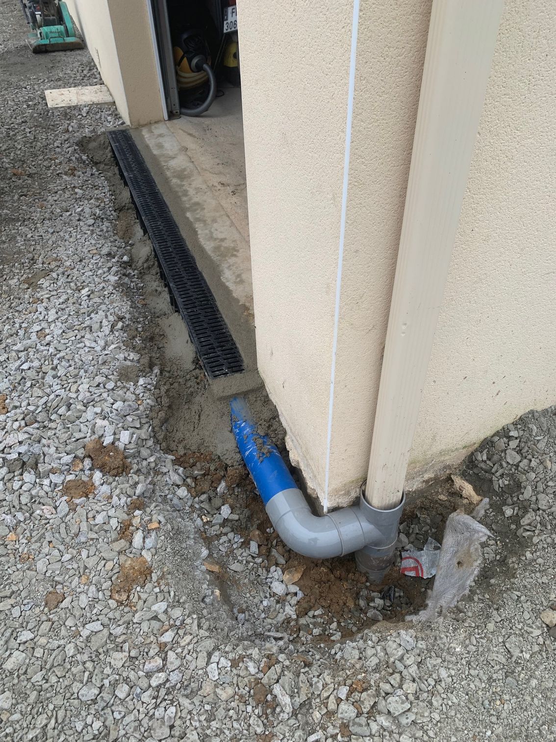 Allée pavée de noir avec bordure en béton, bordée de pelouse et de buissons.