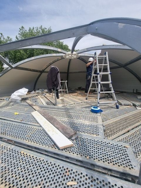 Trabajadores de la construcción instalando paneles de techo en una estructura de cúpula.