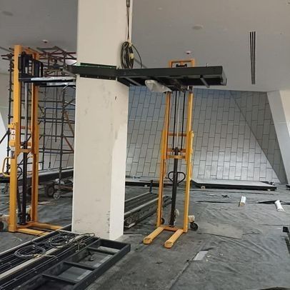 Dos carretillas elevadoras manuales de color amarillo dentro de un edificio en construcción.