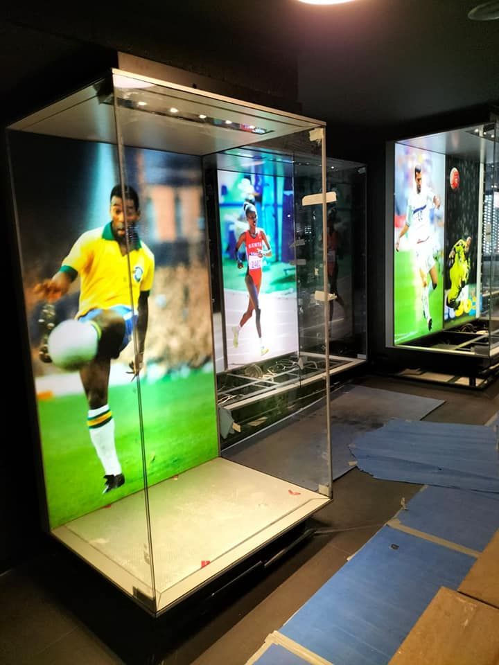 Vitrina que muestra a Pelé jugando al fútbol, ​​con otros dos deportistas en vitrinas similares al fondo.
