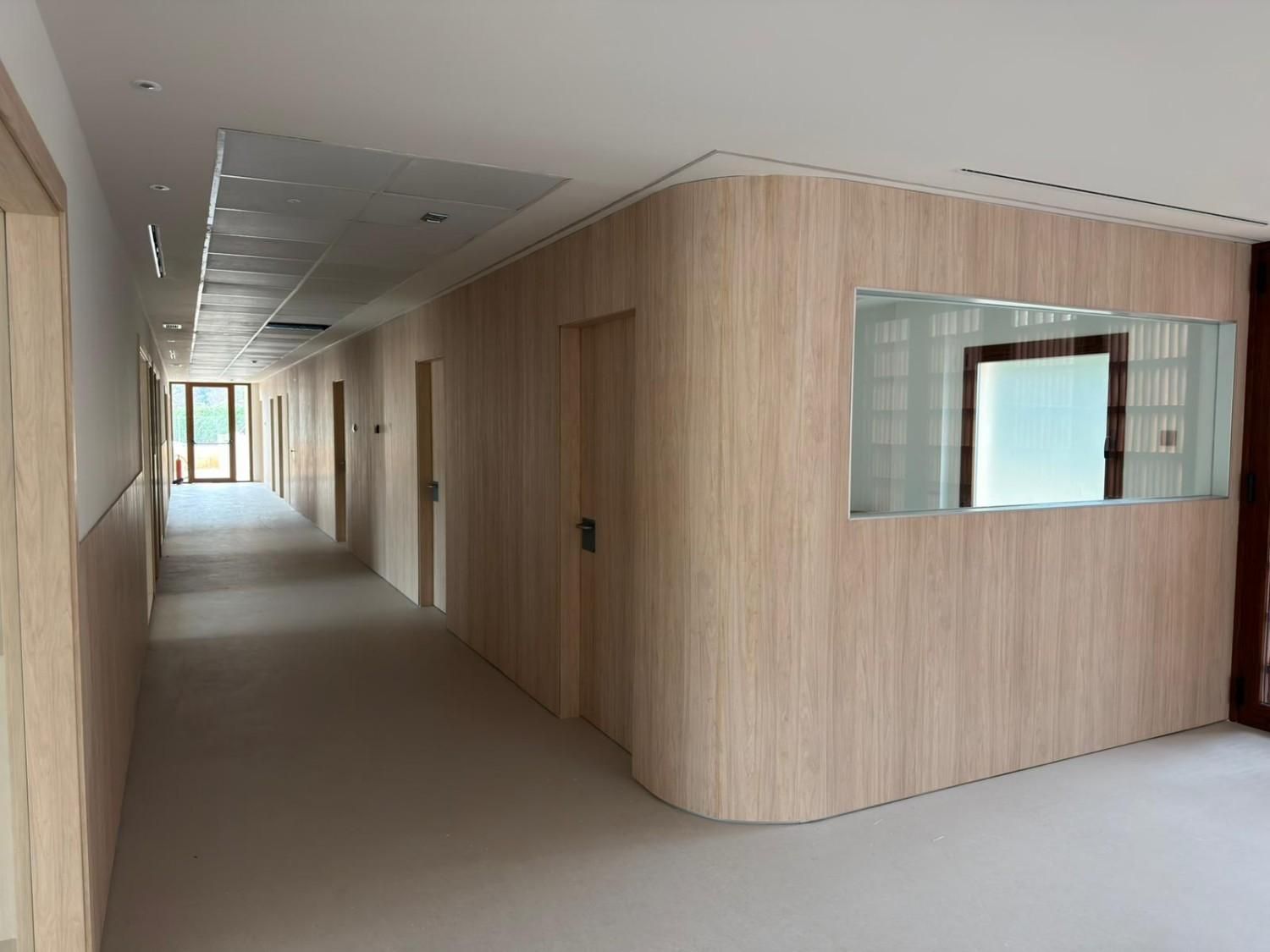 Interior con pared de madera, pantalla de TV, asientos azules y silla blanca.