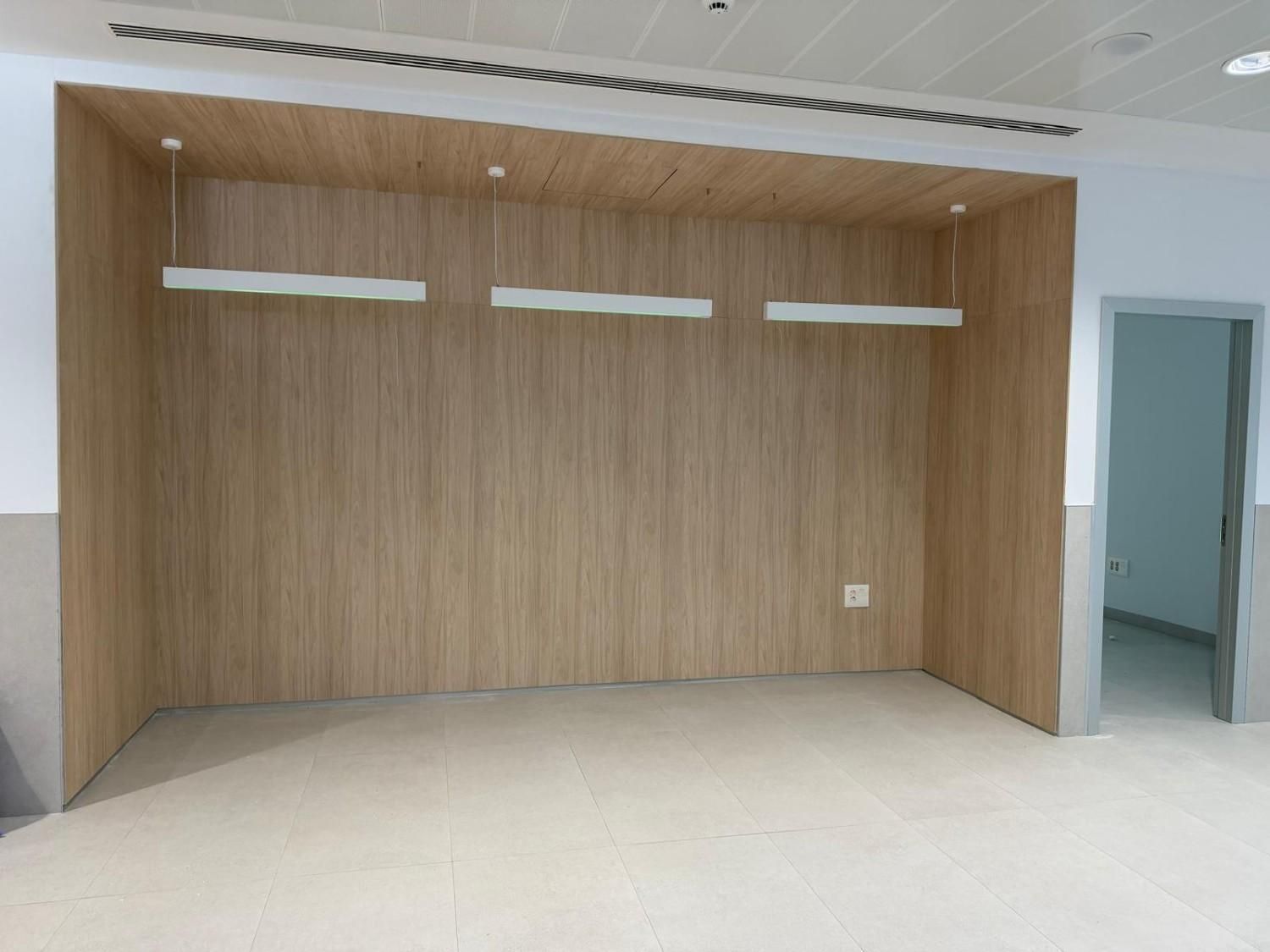 Nicho de madera vacío con tres lámparas colgantes, toma de corriente y puerta abierta.