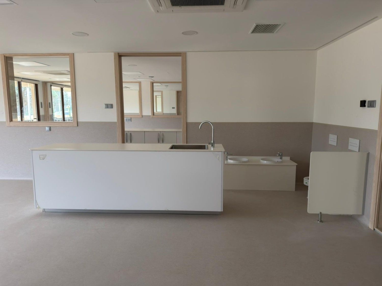 Habitación vacía con muebles blancos, lavabo y paredes neutrales.