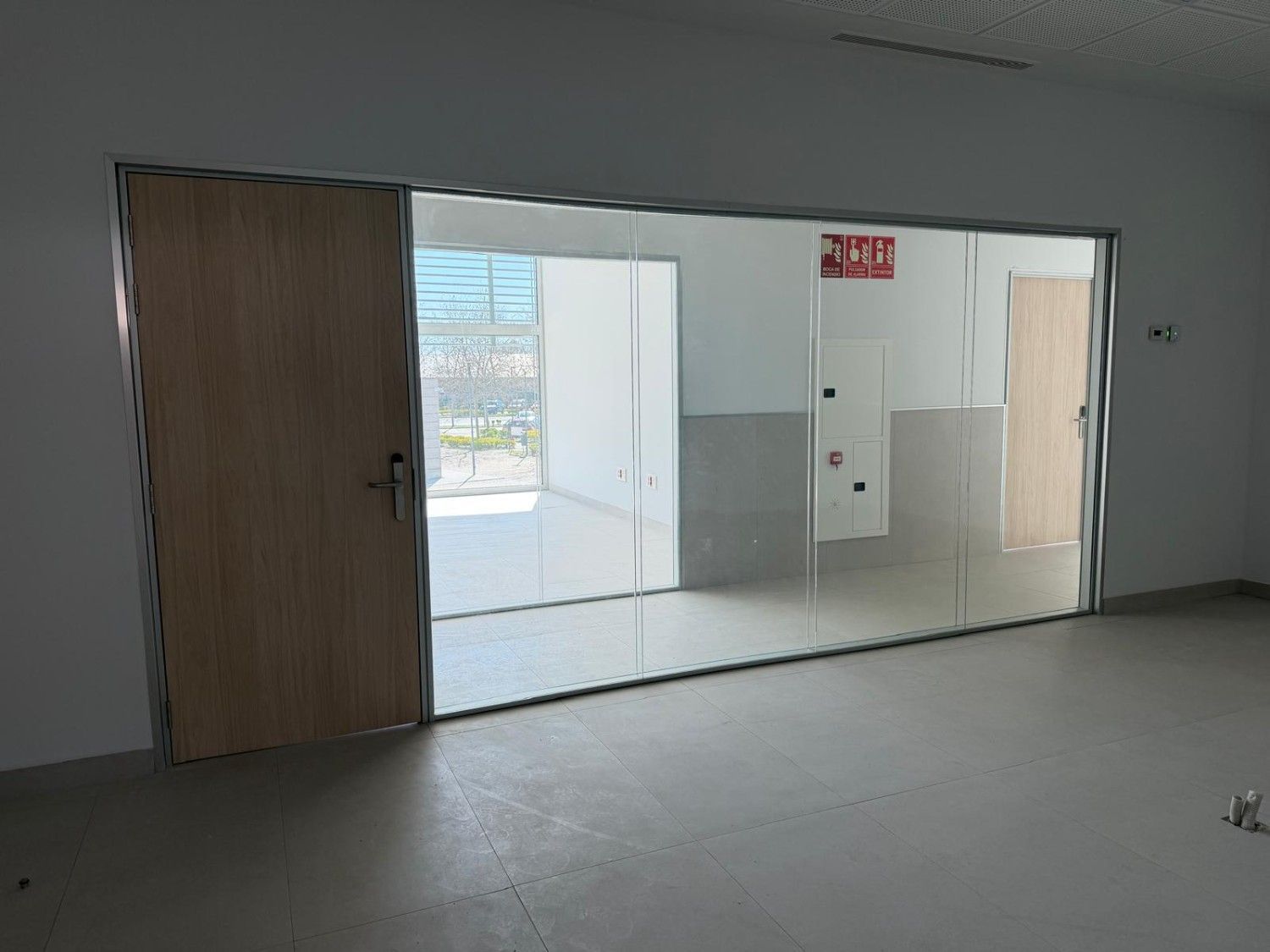 Vista interior de una habitación con un gran panel de vidrio y una puerta de madera.