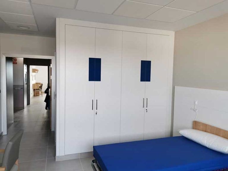 Armario blanco con detalles en azul en un dormitorio, colchón y puerta de color azul.